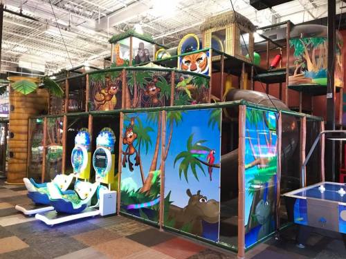 Colorful indoor play structure with jungle-themed decorations, slides, and arcade games for children.