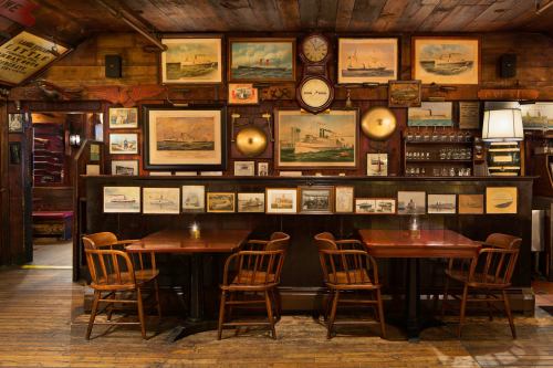 Cozy restaurant interior with wooden tables, chairs, and vintage maritime artwork on the walls. Warm, inviting atmosphere.