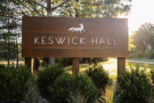 Sign for Keswick Hall surrounded by greenery, with a fox silhouette above the name. Soft sunlight in the background.