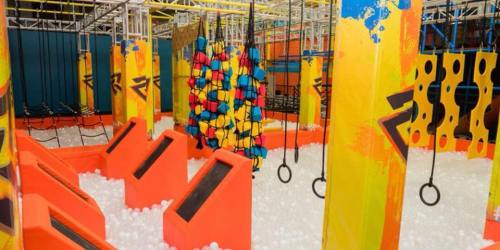 Colorful indoor obstacle course with climbing structures, ropes, and a ball pit.