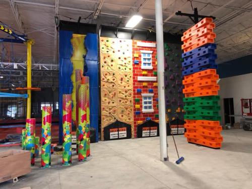 Indoor climbing facility featuring colorful climbing walls and structures in a spacious area.