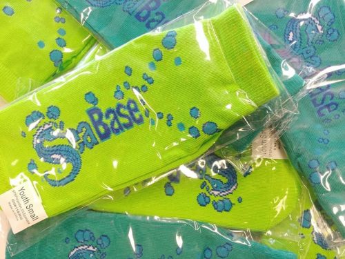 Bright green socks with a blue "SeaBase" logo and bubble designs, packaged and stacked together.