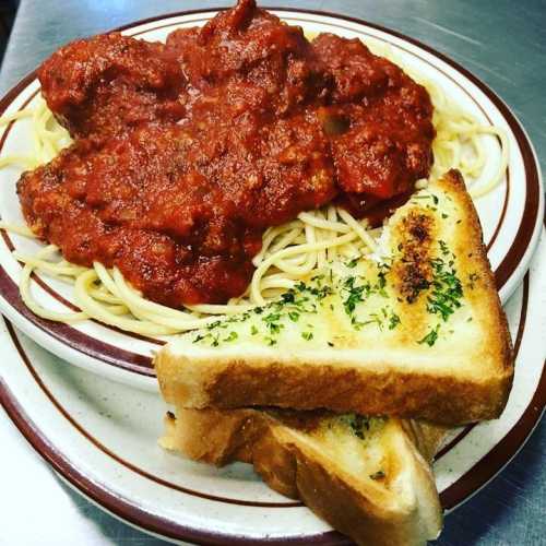 A plate of spaghetti topped with meatballs and marinara sauce, served with slices of garlic bread.