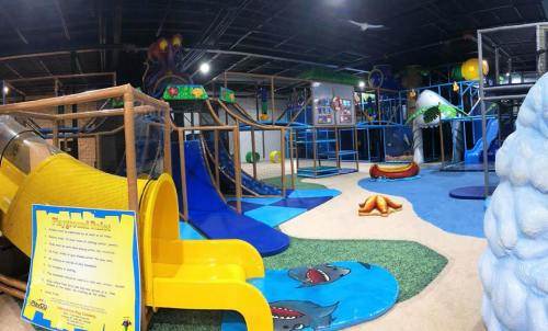Indoor playground featuring slides, climbing structures, and colorful play areas with ocean-themed decorations.