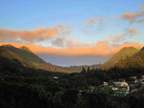 A scenic view of mountains under a colorful sky, with a small village nestled in the valley below.