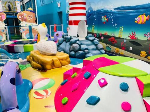 Colorful indoor play area featuring a lighthouse, sea-themed decorations, and various playful structures.