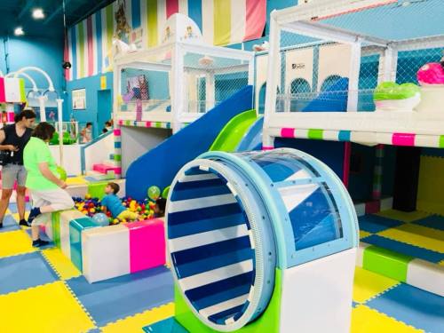 A colorful indoor play area with slides, ball pits, and climbing structures for children.
