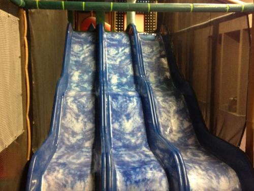 Three blue water slides with a marbled design, set in an indoor play area.