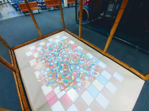 A colorful, patterned projection on a floor inside a bamboo-framed play area.