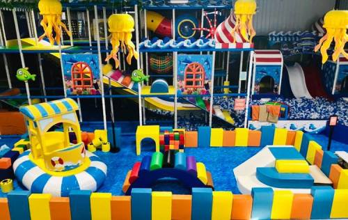 Colorful indoor play area with slides, climbing structures, and soft play equipment for children.