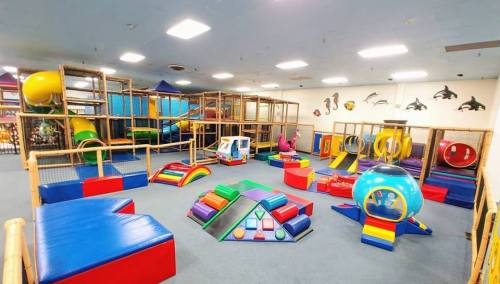Colorful indoor playground with various climbing structures, slides, and soft play areas for children.