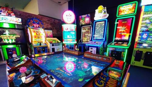 A vibrant arcade filled with colorful gaming machines and bright lights, showcasing various games and attractions.