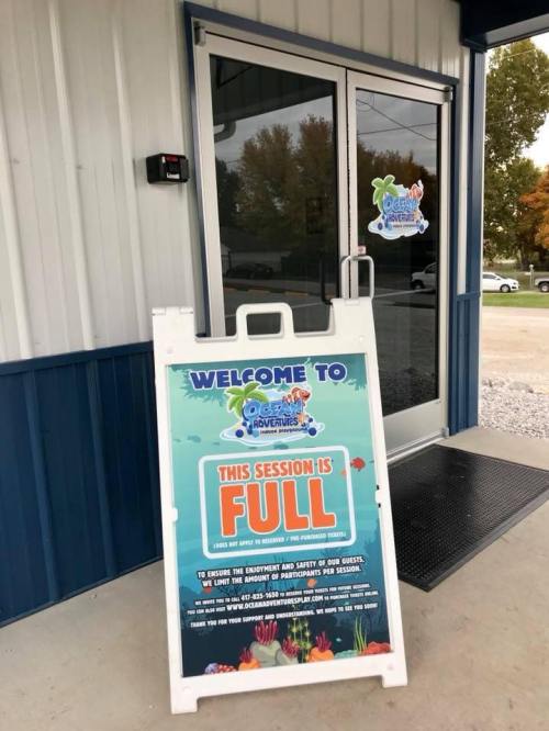 A sign outside a building reads "Welcome to [Business Name] Adventures" and "This session is full."