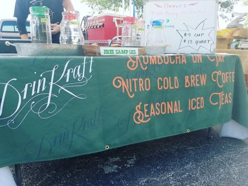 A table display featuring drinks like kombucha, nitro cold brew coffee, and seasonal iced teas, with a "Free Samples" sign.