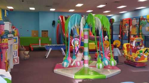 Colorful indoor play area with a carousel, slides, and various play structures for children.