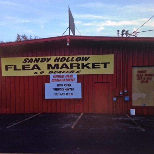 Sign for Sandy Hollow Flea Market, featuring "60 Dealers," with a notice for "Now Open" and "Managers Wanted."