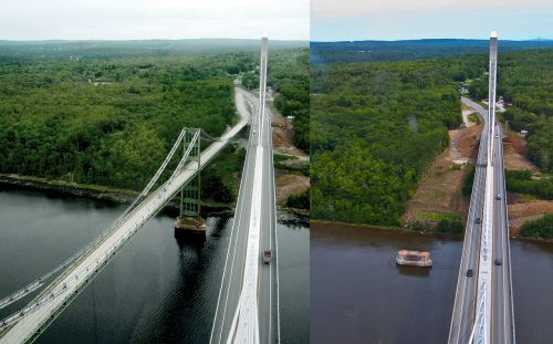Aerial view of two bridges spanning a river, surrounded by lush green forests and a clear sky.