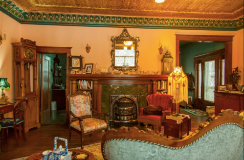Cozy vintage living room with ornate decor, a fireplace, and antique furniture in warm colors.