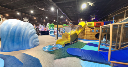 Colorful indoor playground featuring a slide, climbing structures, and ocean-themed decorations.
