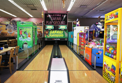 Colorful arcade games and a bowling lane in a vibrant indoor playground called "Safari Playground."
