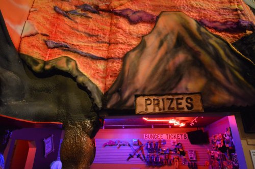 Colorful mural of mountains with a sign reading "PRIZES" and a display of bungee tickets in a fun, vibrant setting.