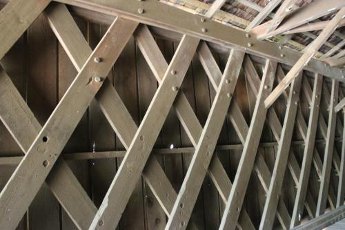 Close-up of a wooden wall with diagonal beams creating a crisscross pattern, showcasing rustic construction details.