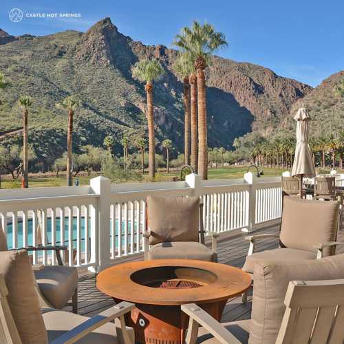 A scenic view of mountains and palm trees from a patio with seating and a fire pit.