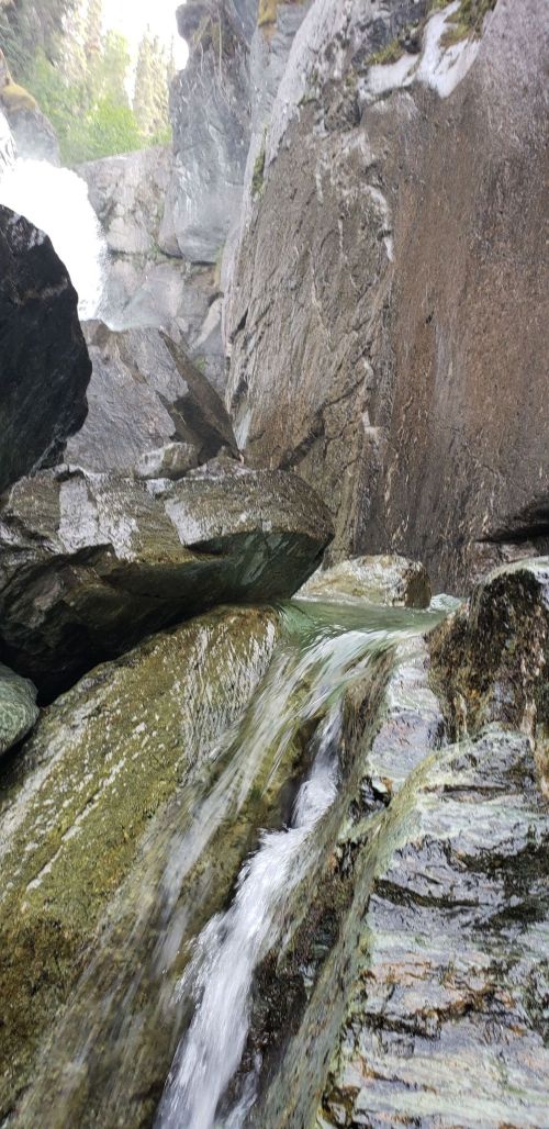 A close-up view of a rocky waterfall, with water cascading over moss-covered stones and flowing down the rocks.