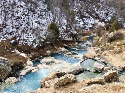 A serene landscape featuring a winding river with turquoise water, surrounded by rocky terrain and sparse trees.