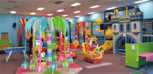 Colorful indoor play area featuring inflatable structures, slides, and play equipment for children.