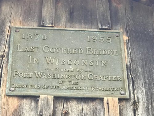 Plaque on a wooden structure, marking the last covered bridge in Wisconsin, established 1876, dedicated 1955.