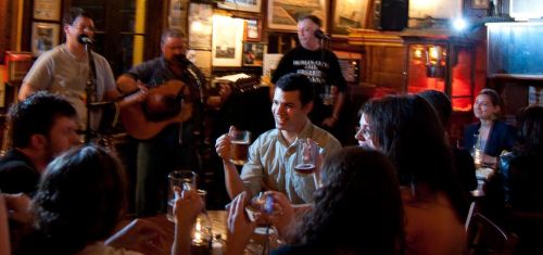 A lively pub scene with a band playing, people enjoying drinks, and a cheerful atmosphere.