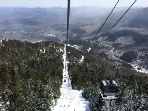 A scenic view from a ski lift, overlooking snow-covered mountains and valleys under a clear sky.