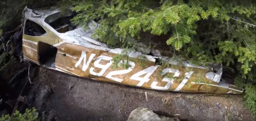 An abandoned aircraft fuselage partially covered by foliage and forest debris, with the tail number N92431 visible.