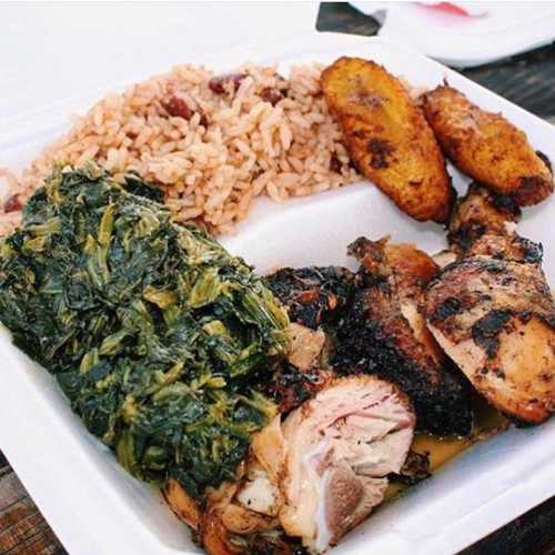 A plate of food featuring grilled chicken, rice and beans, sautéed greens, and fried plantains.