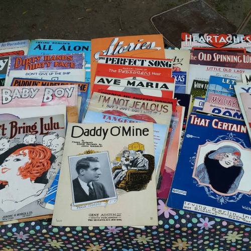 A collection of vintage sheet music covers featuring colorful illustrations and titles from various songs.