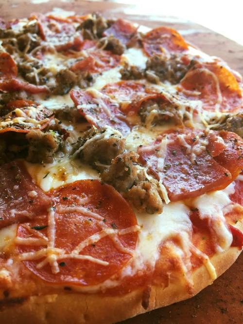 Close-up of a pizza topped with pepperoni, sausage, and melted cheese on a golden crust.