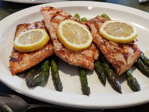 Grilled salmon fillets topped with lemon slices, served on a bed of asparagus.
