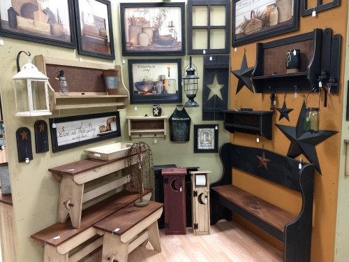 A display of rustic home decor featuring shelves, frames, and furniture with star motifs and warm wood tones.