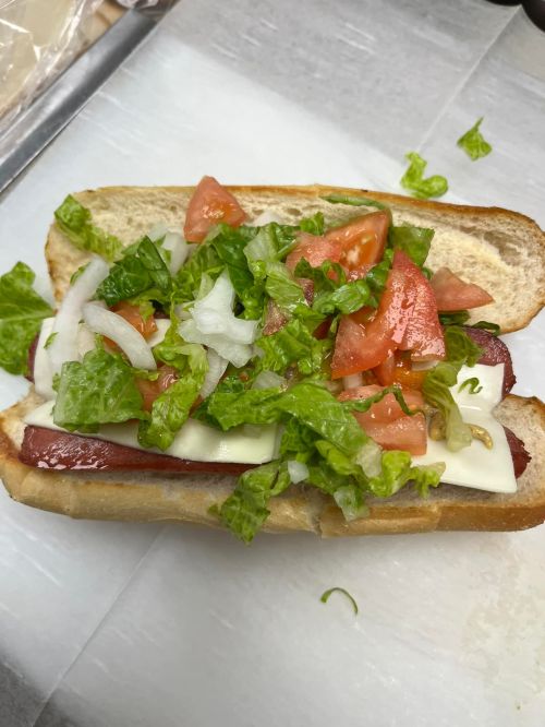A sandwich with layers of lettuce, tomato, onion, and cheese on a toasted hoagie roll.