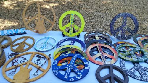 A display of colorful peace sign decorations in various designs and materials on a table outdoors.
