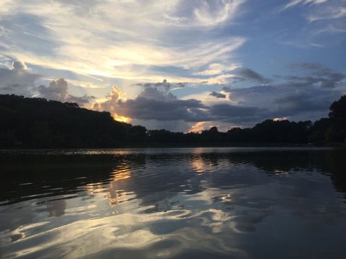 A serene lake at sunset, with colorful clouds reflecting on the water's surface.