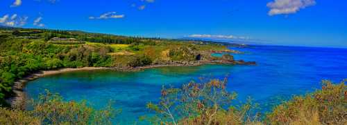 A scenic coastal view featuring clear blue waters, lush greenery, and a bright blue sky with scattered clouds.