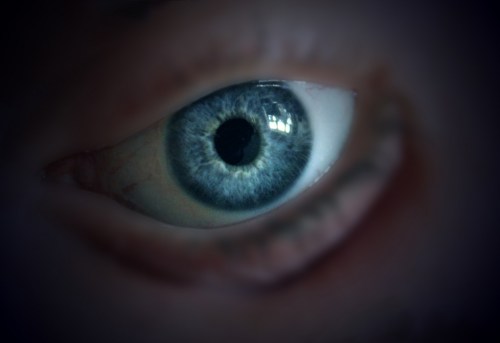 Close-up of a blue eye with intricate details and reflections, set against a dark background.