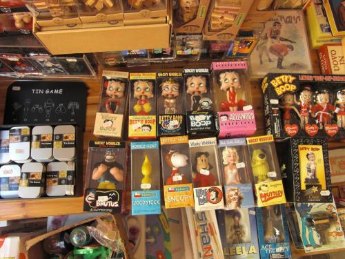 A colorful display of vintage toys and collectibles, including Betty Boop and Snoopy figures, arranged on a wooden shelf.