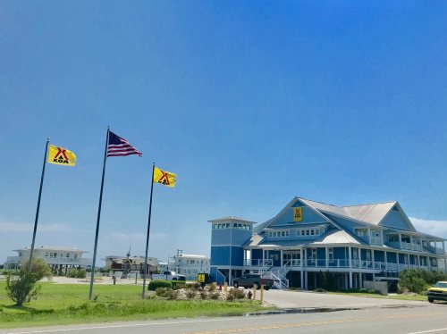 A KOA campground building with flags, including the American flag, under a clear blue sky.