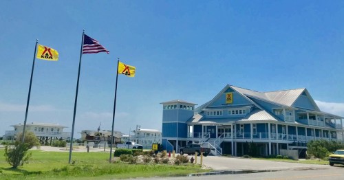 A KOA campground building with flags, including the American flag, under a clear blue sky.