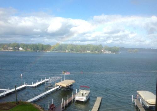 A serene lake view with docks, boats, and a rainbow in the distance under a cloudy sky.