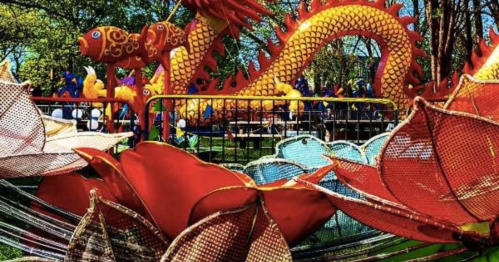 Colorful dragon and flower decorations at a vibrant outdoor festival, surrounded by greenery and festive atmosphere.