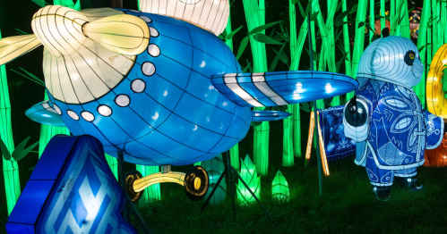 Colorful lanterns shaped like a blue airplane and a stylized animal, surrounded by vibrant green bamboo lights.